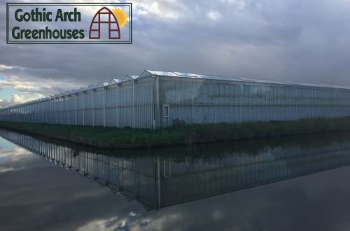 Galvanized steel greenhouse frame under construction on a farm site